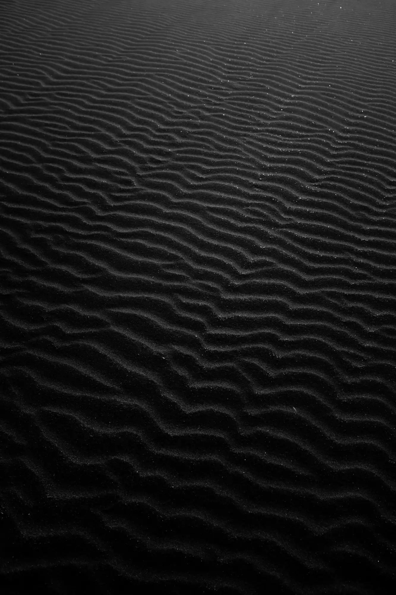 Black sand with fine, wavy ridges.