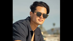 A pair of stylish, dark-tinted sunglasses with a gold-toned metal frame and classic round lenses.
