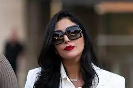 A woman wearing oversized black sunglasses with reflective lenses and a white blazer.